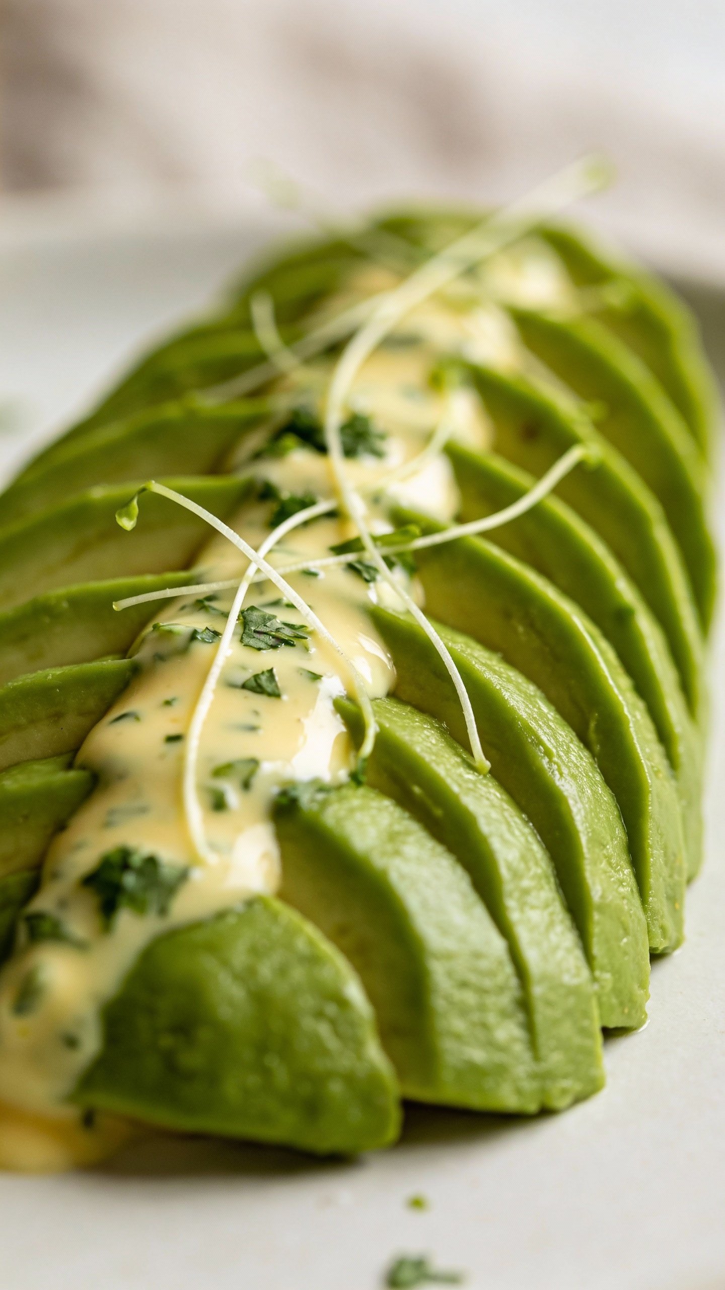 creamy cilantro-lime dressing drizzle on avocado fan, macro shot