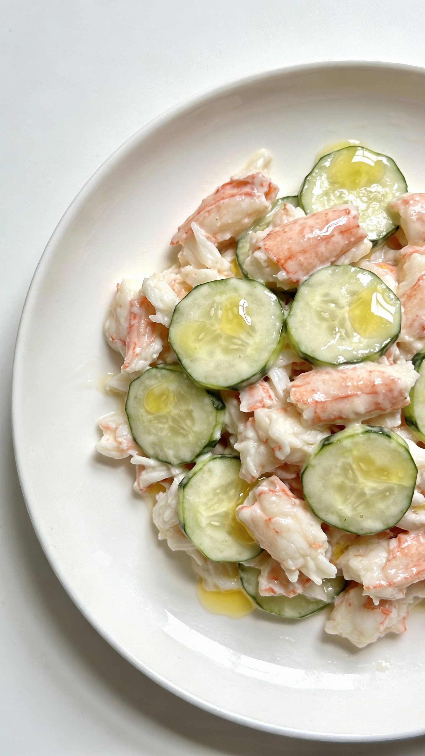 overhead white plate of crab-cucumber salad, lemon dressing sheen