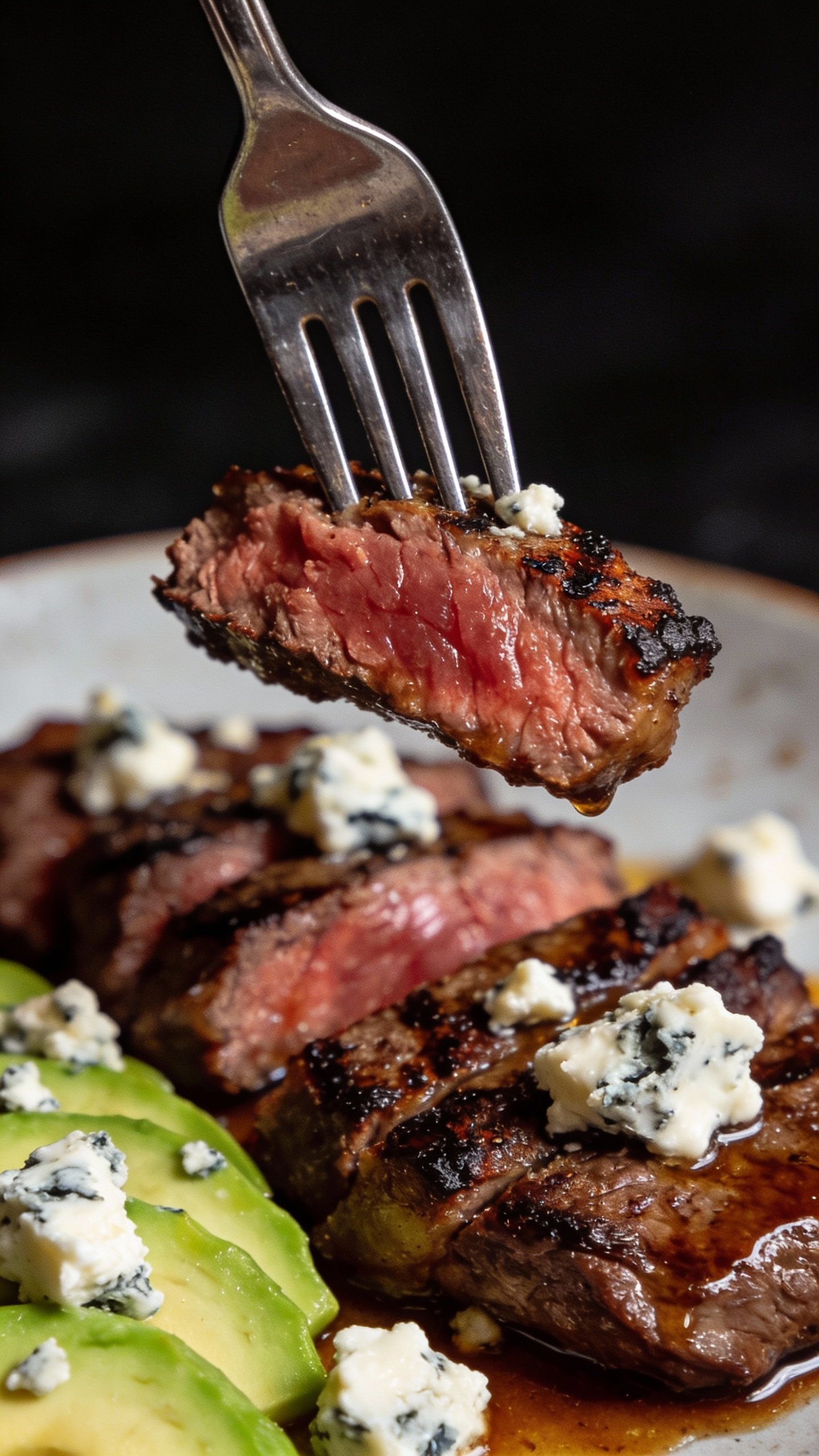 forkful of steak, blue cheese, and avocado against dark background