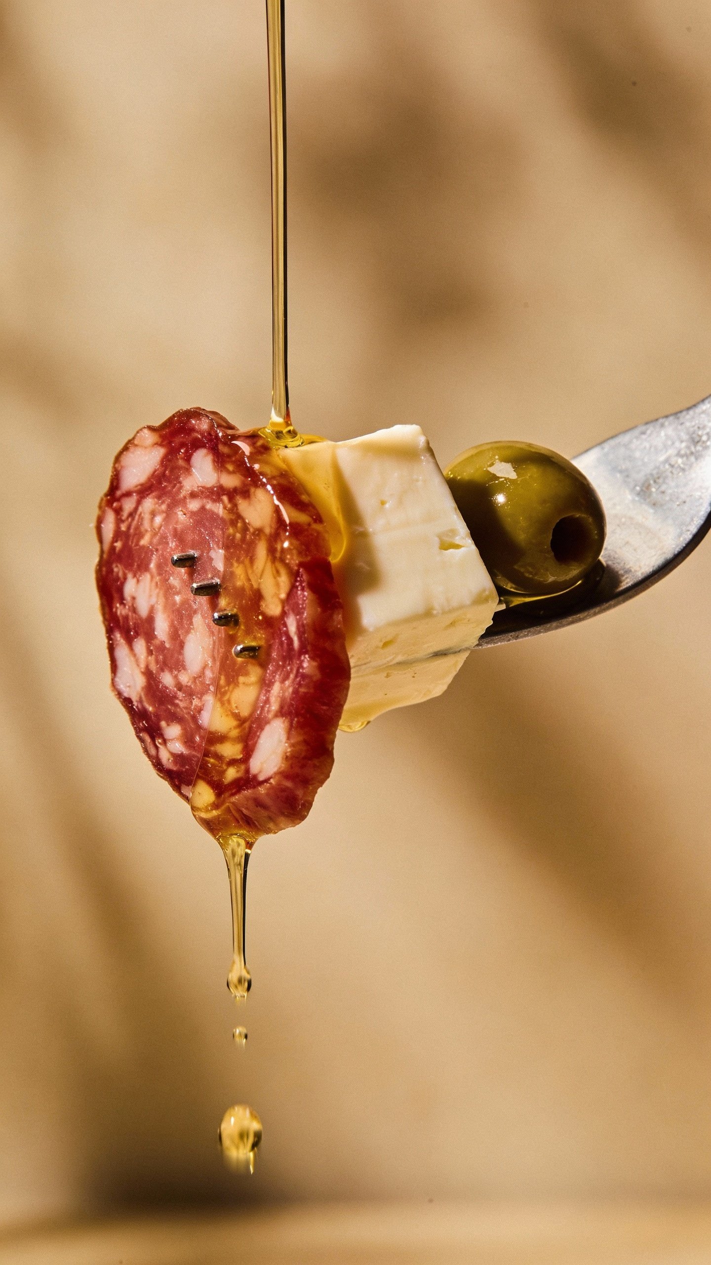 single forkful of salami, provolone, olive, vinaigrette drips
