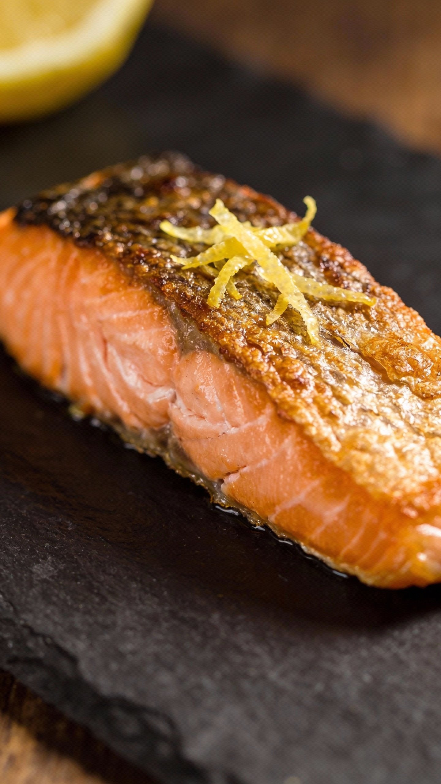 closeup seared salmon fillet with lemon zest on slate