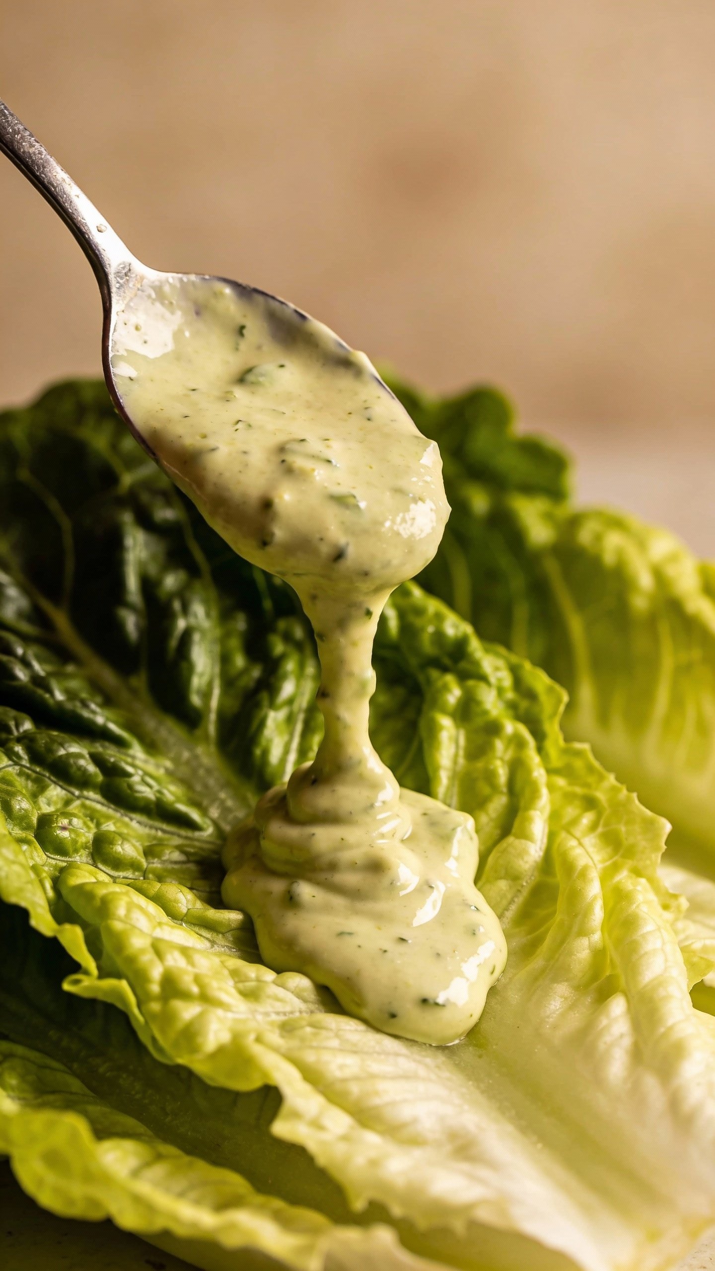 spoon dripping creamy avocado ranch over romaine leaf