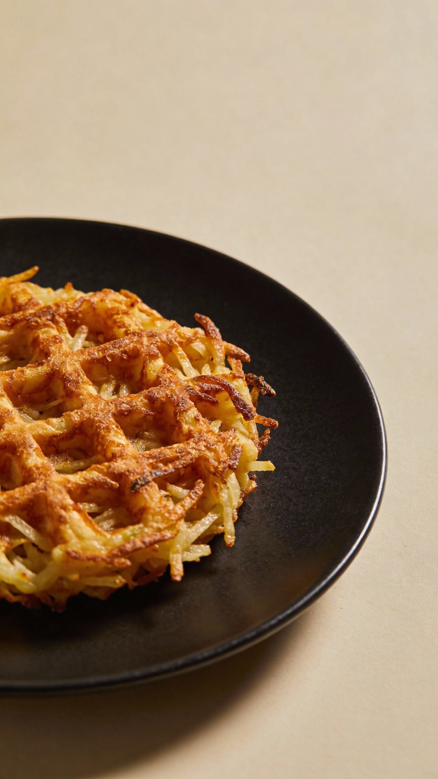 closeup of single keto hash brown waffle on matte black plate