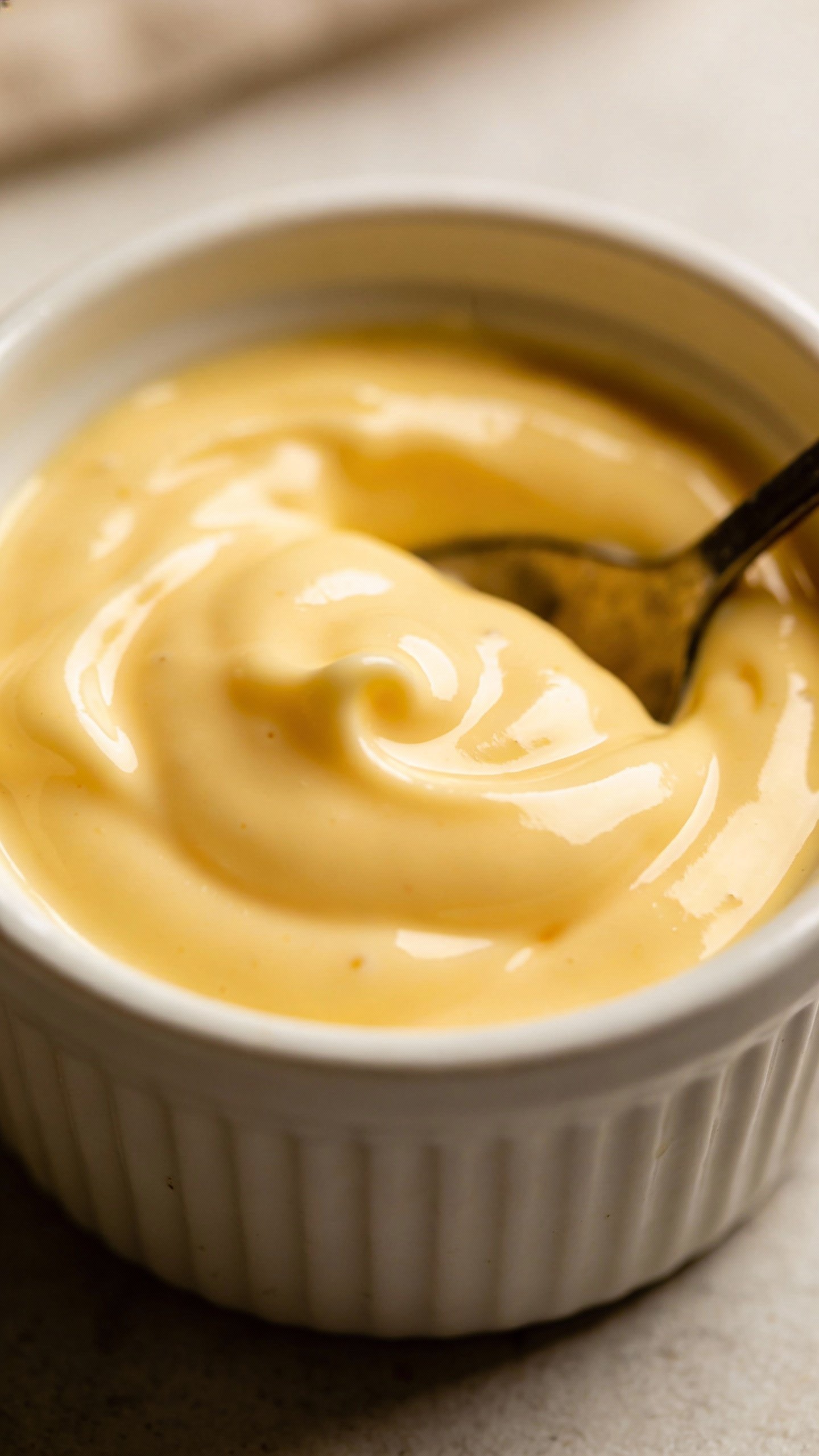 silky hollandaise sauce in small ramekin with spoon marks
