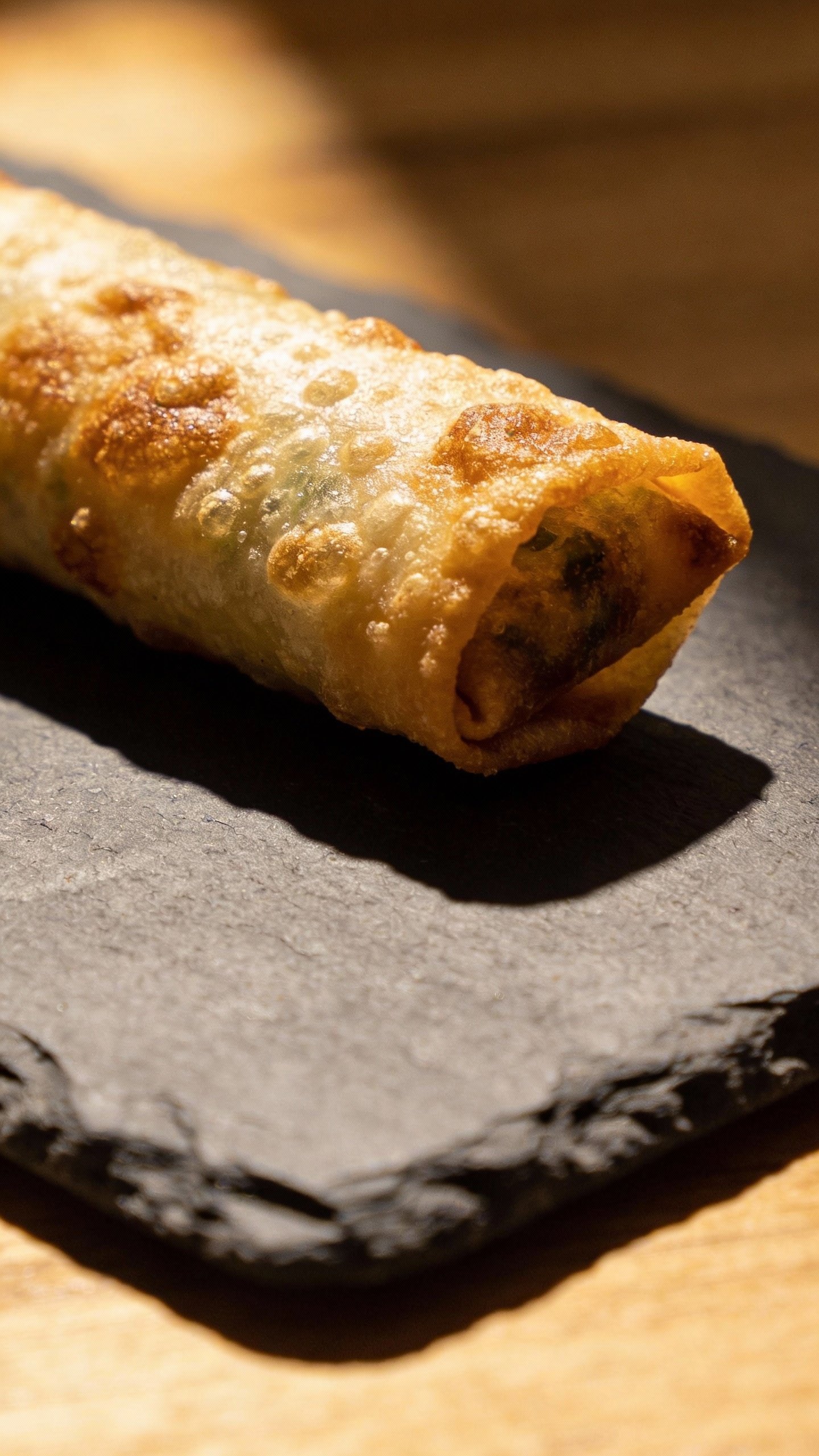 single keto egg roll on slate board, crispy blistered wrapper