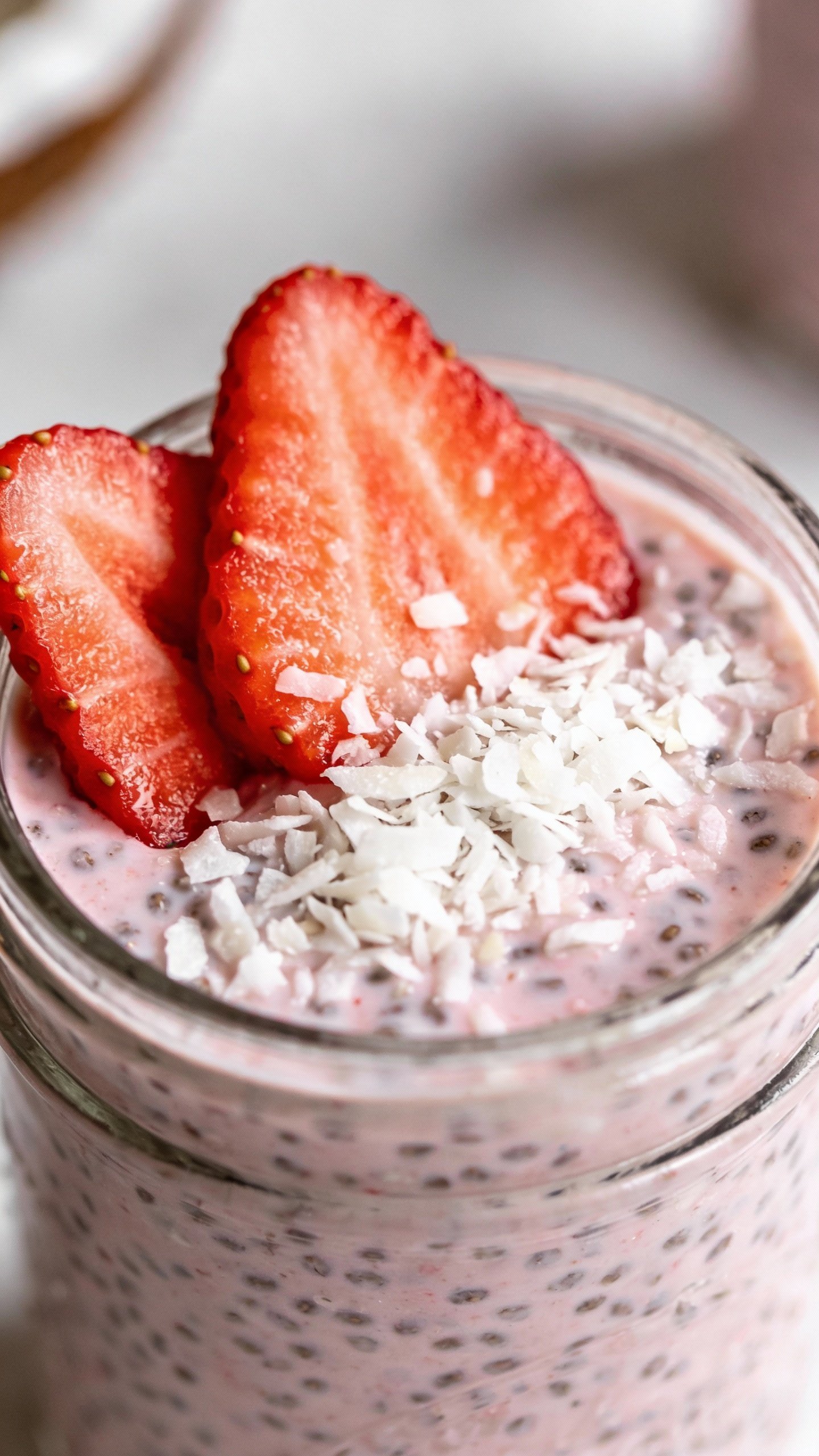 closeup strawberry coconut chia pudding in clear glass jar