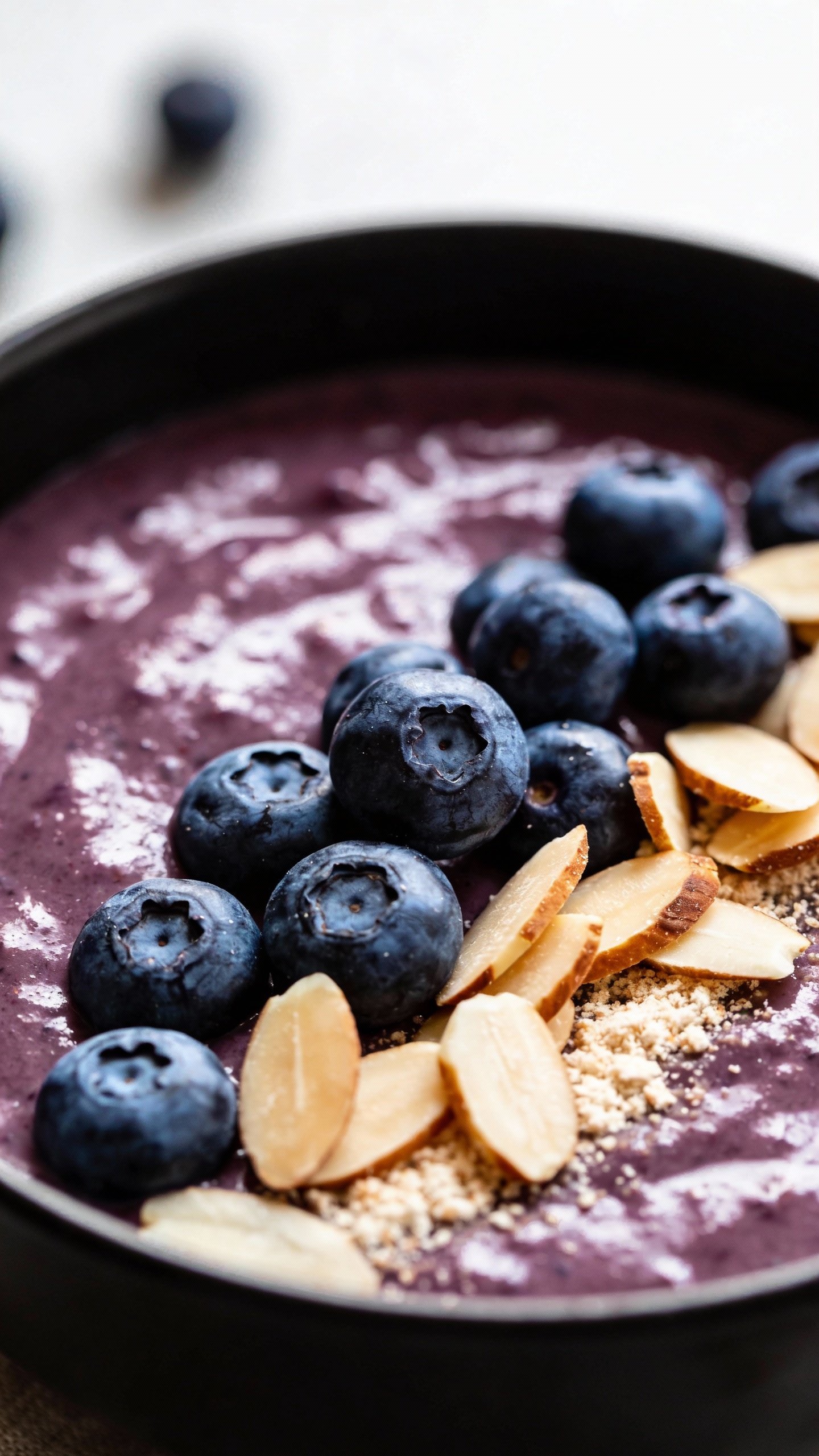 closeup blueberry almond keto smoothie bowl, matte black bowl