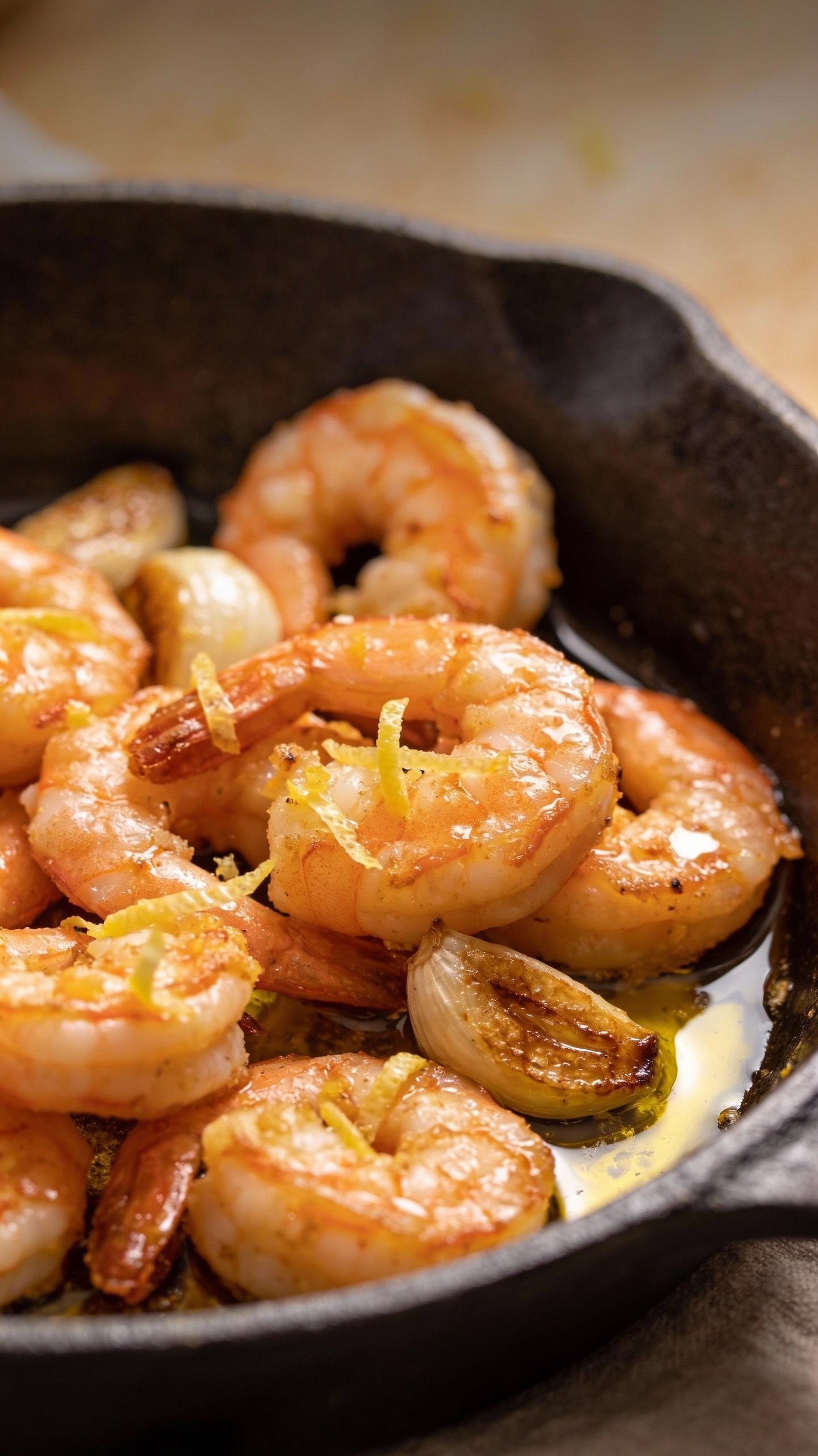 single skillet of buttery garlic shrimp, lemon zest garnish