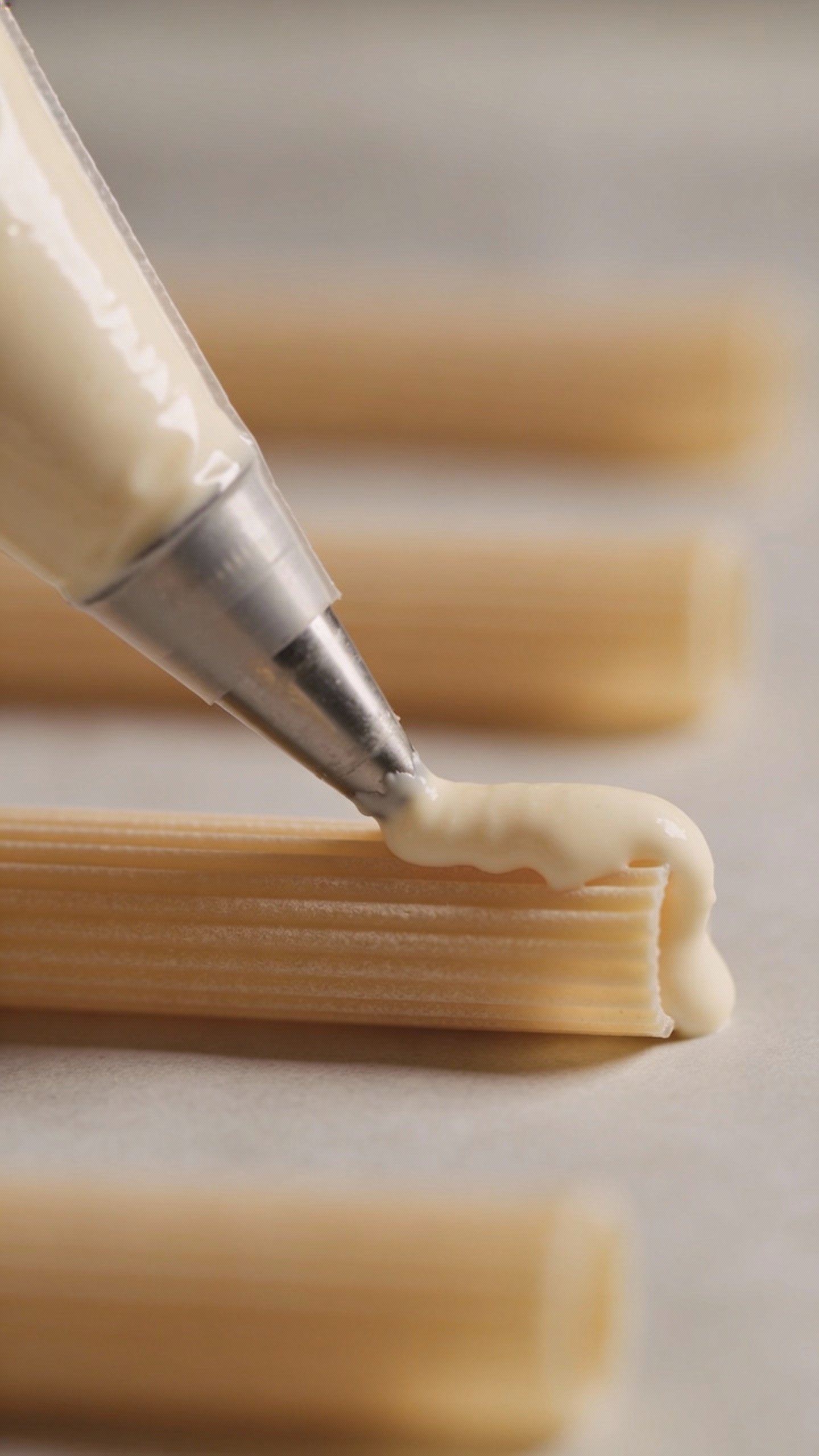 piping bag filling a single manicotti tube, macro shot