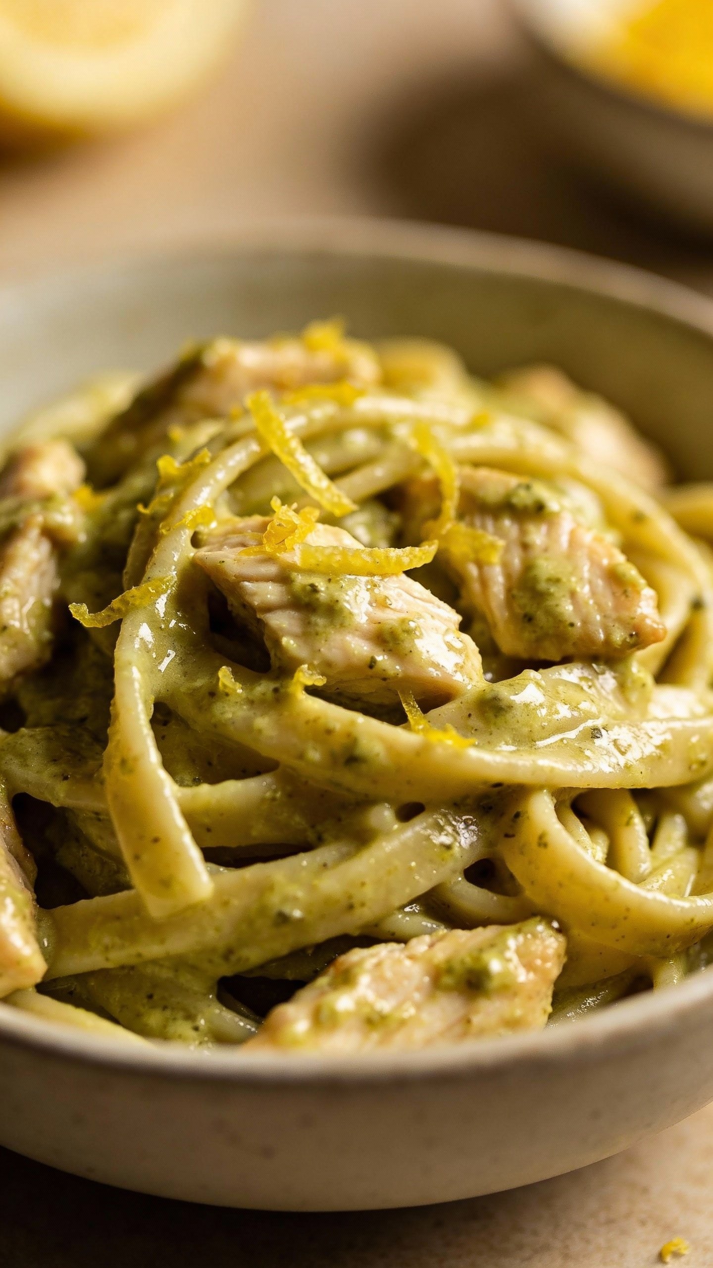 closeup bowl of creamy pesto chicken pasta with lemon zest