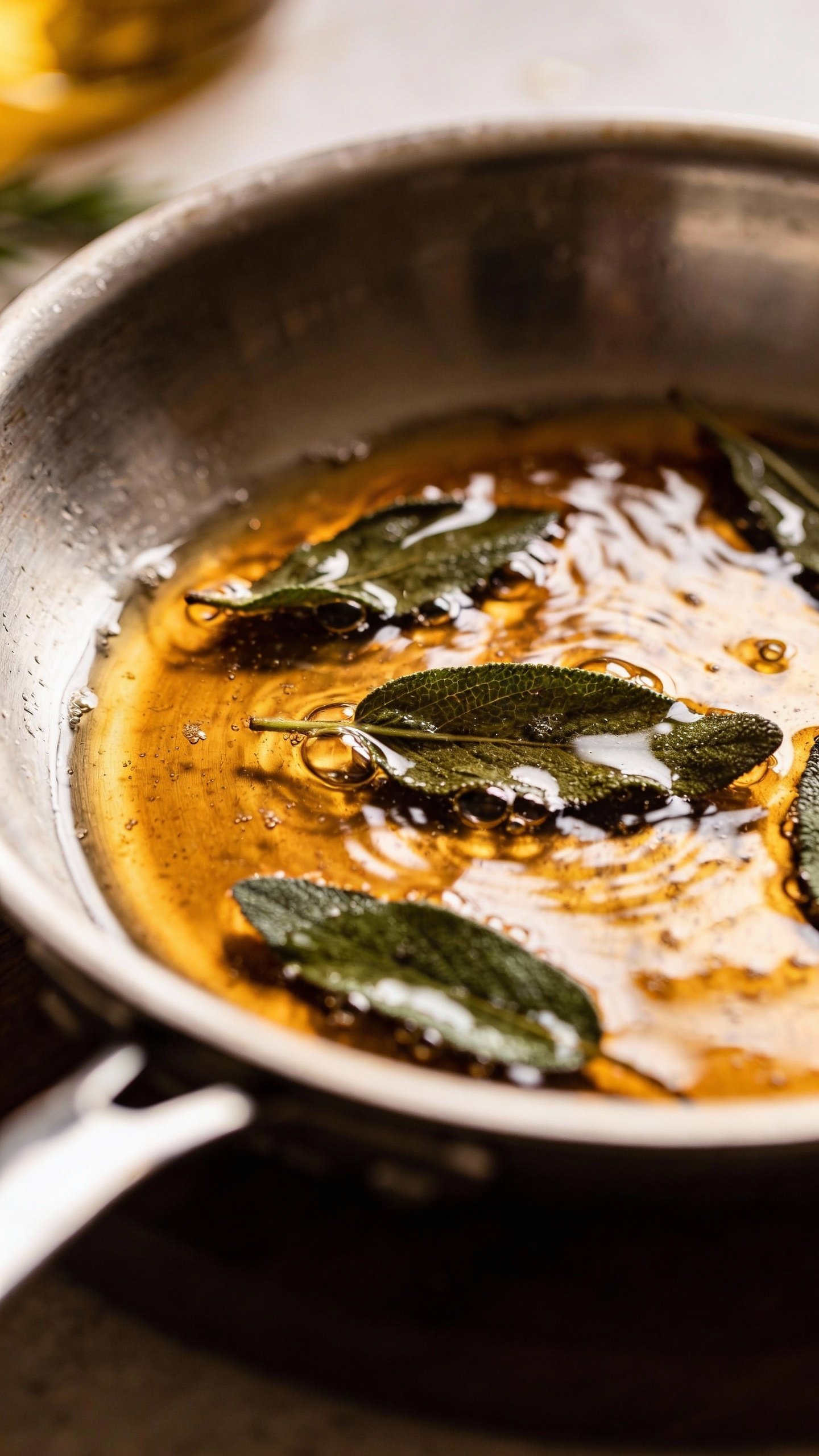 sizzling brown butter with crispy sage leaves in stainless skillet