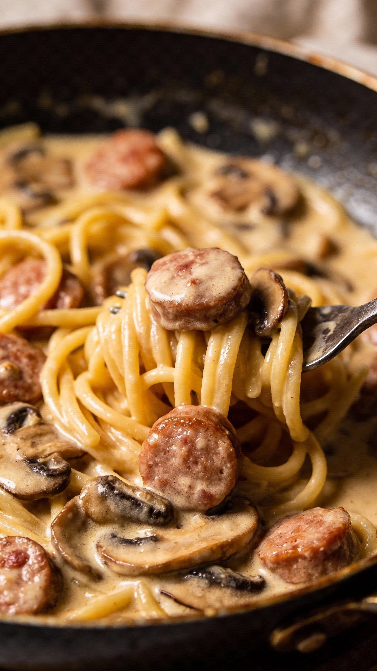 Closeup of sausage and mushroom cream sauce pasta in skillet