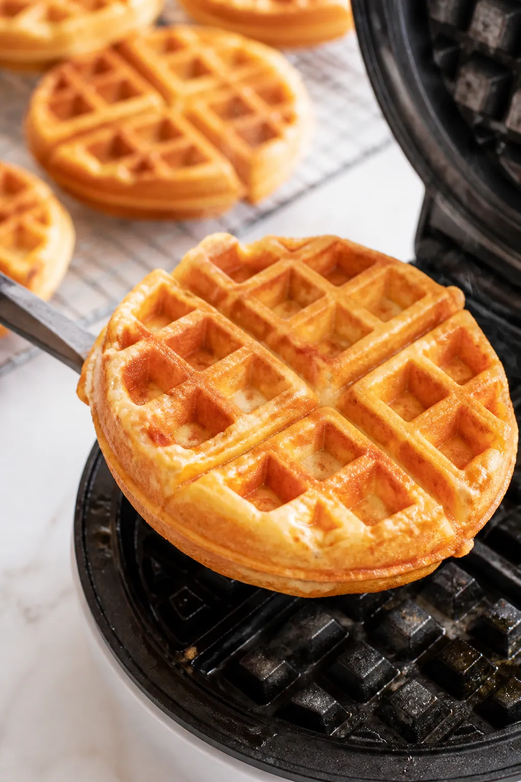 Close-up cooking process: Golden cottage cheese oat waffle just lifted from a hot waffle iron, steam