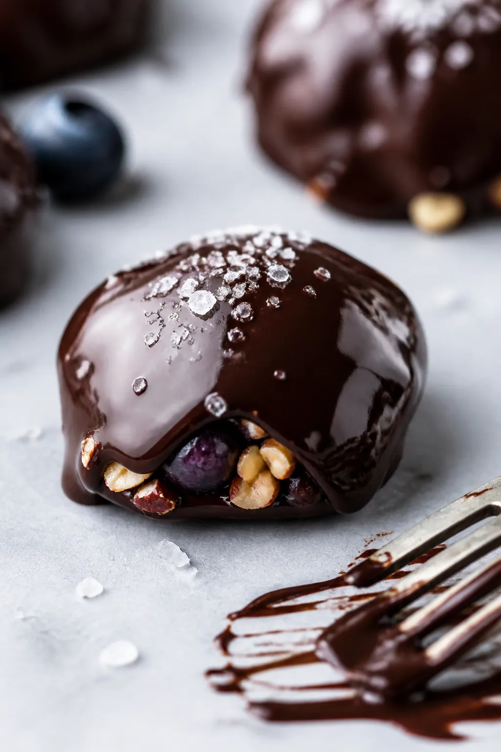 Close-up detail: A just-dipped chocolate-covered Greek yogurt cluster resting on parchment, glossy d