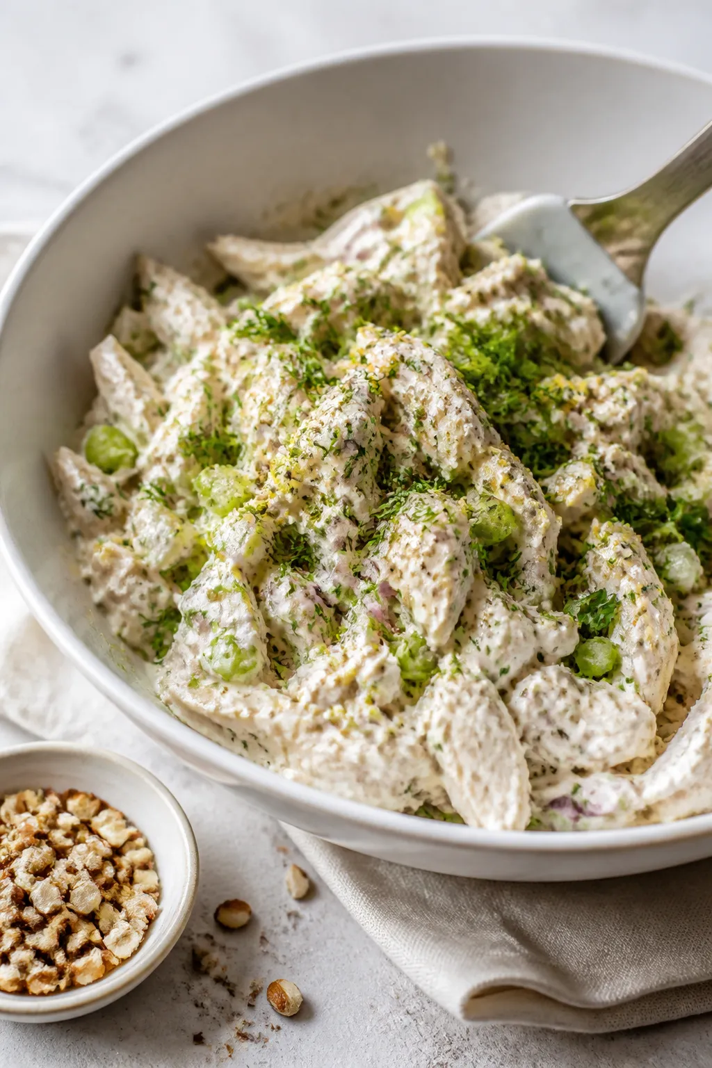 Close-up detail/process: Chilled, finely chopped chicken being gently folded into a creamy Greek yog