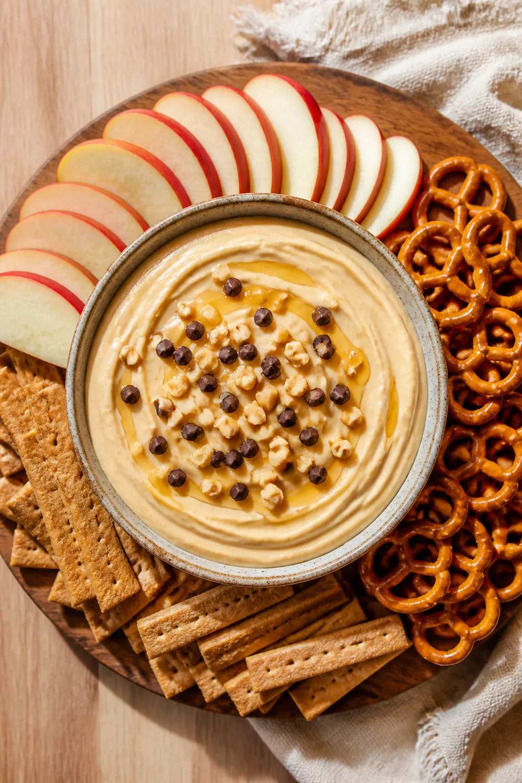 Overhead shot of a creamy peanut butter Greek yogurt dip in a low, wide ceramic bowl, glossy swirls