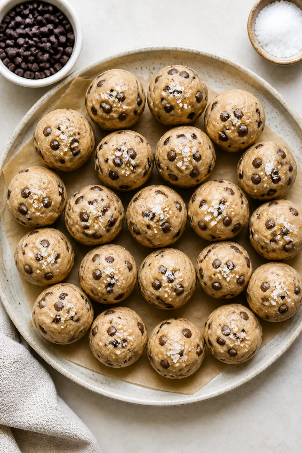 Overhead shot of chilled High Protein Cookie Dough Bites arranged in tight rows on a parchment-lined